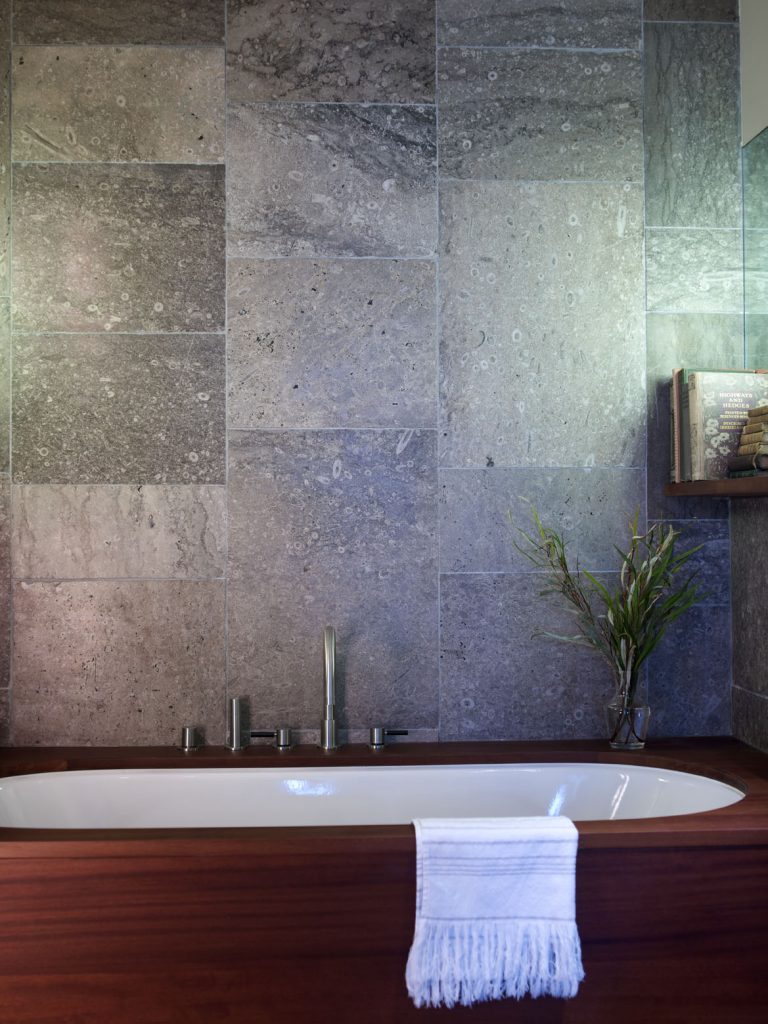 Iroko bath surround with limestone tiles